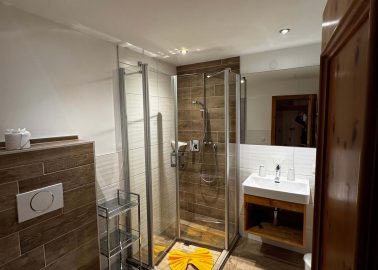 Modernes Badezimmer mit Dusche, WC und Holzdetails in warmer Atmosphäre.